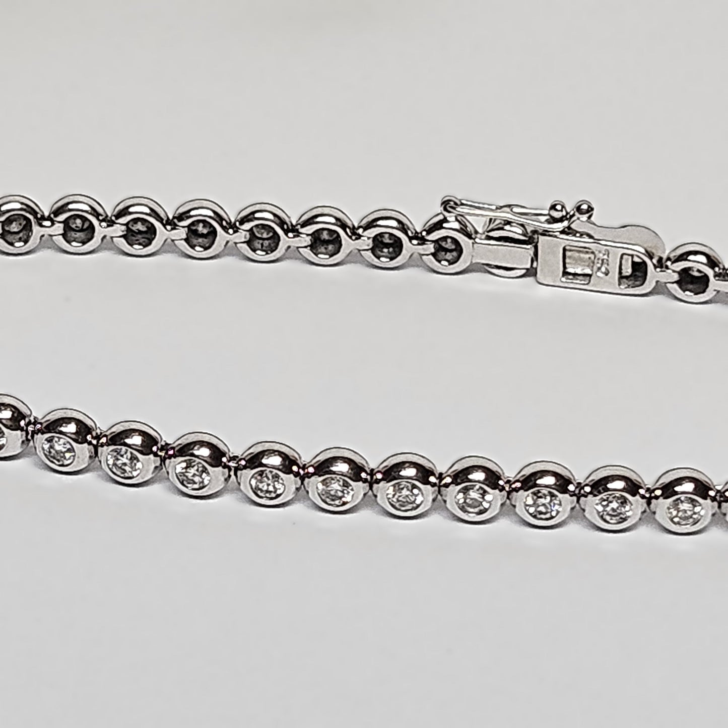 Tennis bracelet with rubbed in diamond settings